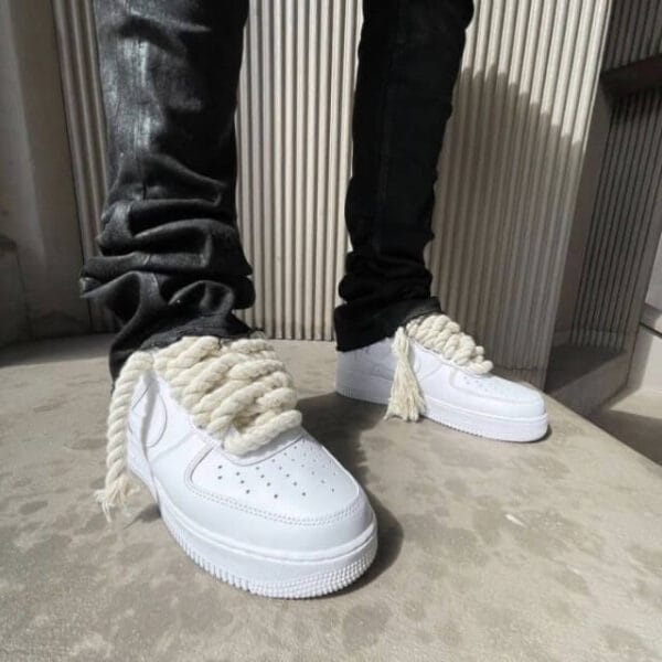 "A stylish individual wearing Nike Air Force 1 sneakers with chunky white laces, paired with a clean and modern streetwear outfit for a fresh, standout look.