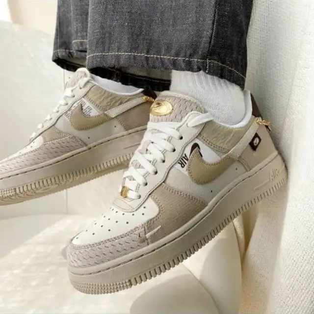 Nike Air Force 1 '07 LX 'Tan Bling' styled on a lady wearing white socks and black jeans, showcasing the sneaker’s premium suede, gold accents, and timeless AF1 design.