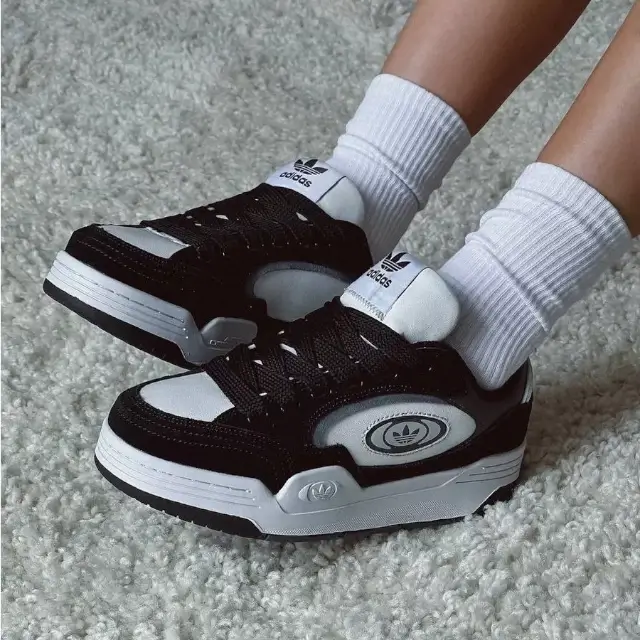 Adidas Adi2000 X Black & White styled on a lady wearing white socks, showcasing the sneaker’s premium leather upper, chunky rubber sole, and bold 3-Stripes branding