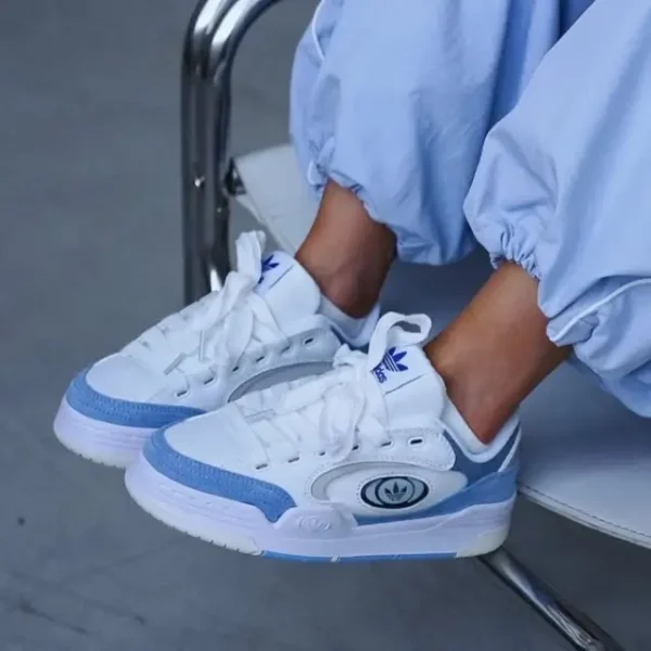 "Adidas Adi2000 X Blue styled on a lady wearing blue trousers, showcasing the sneaker’s pastel blue suede upper, chunky rubber sole, and bold black Adidas branding